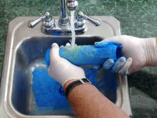 Cleaning a roller in a sink.